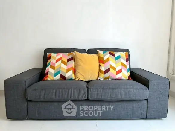 Modern gray sofa with colorful geometric pillows in a bright living room.