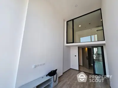 Modern minimalist studio apartment with high ceilings, large mirror, and sleek finishes, perfect for urban living.