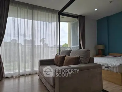 Modern bedroom with large windows and cozy seating area, offering natural light and serene views.