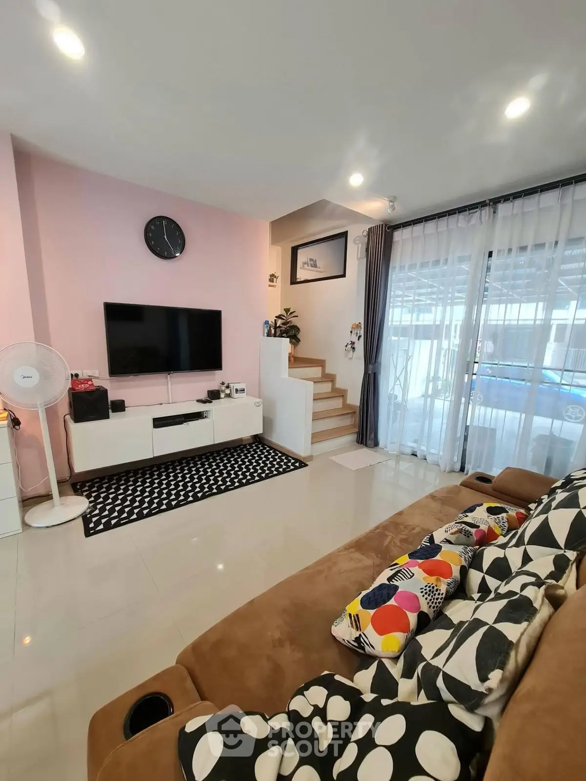 Modern living room with stylish decor, large TV, and cozy seating area.