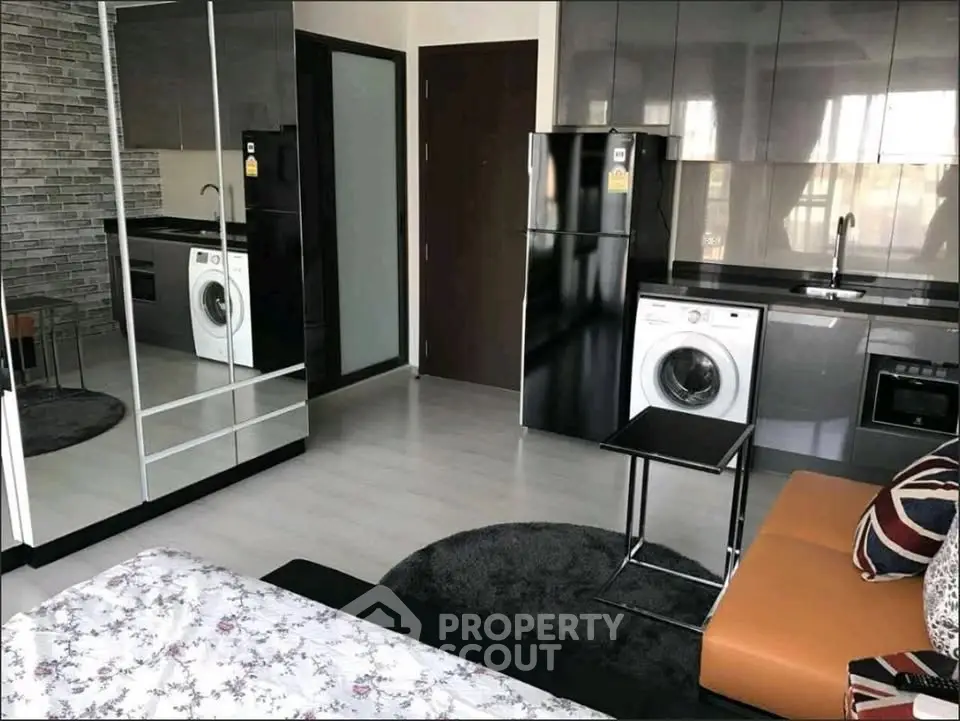 Modern studio apartment with sleek kitchen and mirrored wardrobe