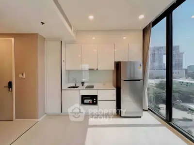 Modern kitchen with sleek white cabinets and stainless steel appliances in a high-rise apartment.