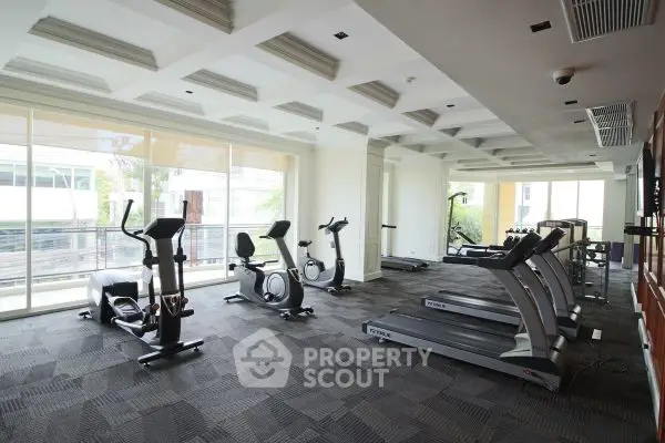 Modern gym with cardio equipment and large windows in a luxury apartment building.
