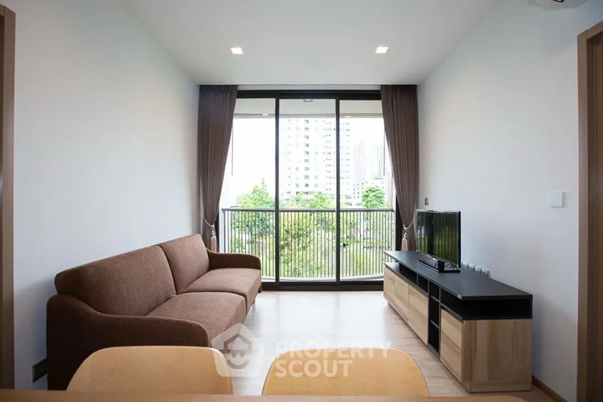 Modern living room with large window and city view, featuring a cozy brown sofa and sleek TV stand.