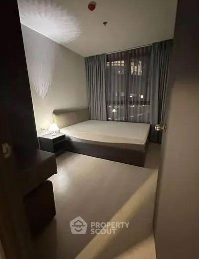Cozy bedroom with modern decor and large window offering city views.