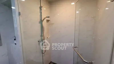 Modern bathroom with sleek glass shower enclosure and marble walls