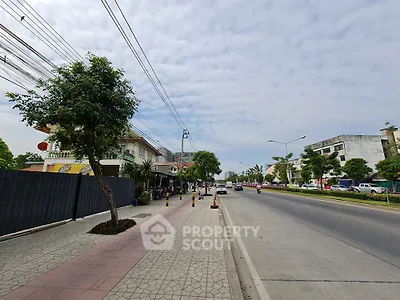 Spacious urban street view with sidewalk and trees, ideal for commercial real estate opportunities.