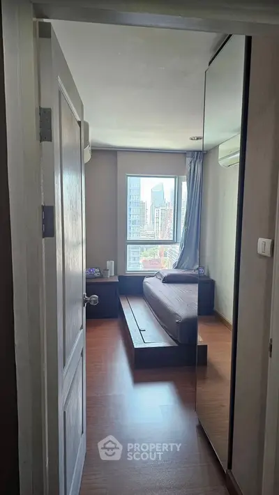 Modern bedroom with city view, featuring sleek design and natural light.