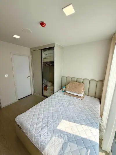 Cozy bedroom with modern design and ample natural light, featuring a comfortable bed and built-in wardrobe.