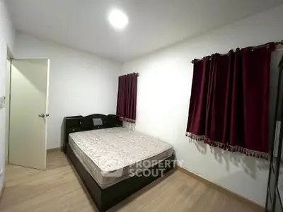 Spacious bedroom with wooden flooring and dark curtains, perfect for comfort and relaxation.