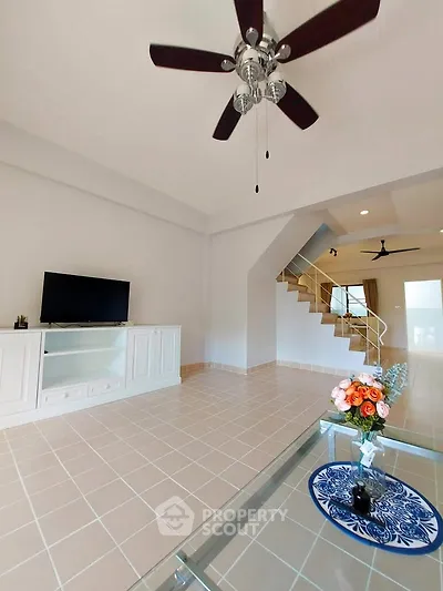 Spacious living room with ceiling fan and modern decor in a bright, open-concept home.