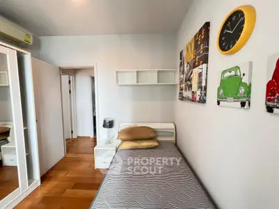 Cozy bedroom with modern decor, featuring a single bed, wall art, and wooden flooring.
