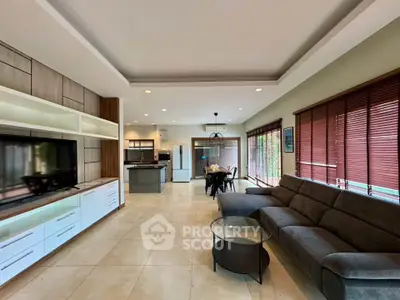 Spacious open-plan living room with modern kitchen and large windows.