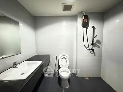 Modern bathroom with sleek fixtures and a spacious layout, featuring a shower and large mirror.
