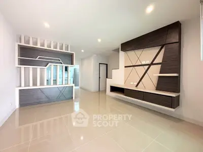 Spacious modern living room with sleek built-in shelving and glossy tiled floors.
