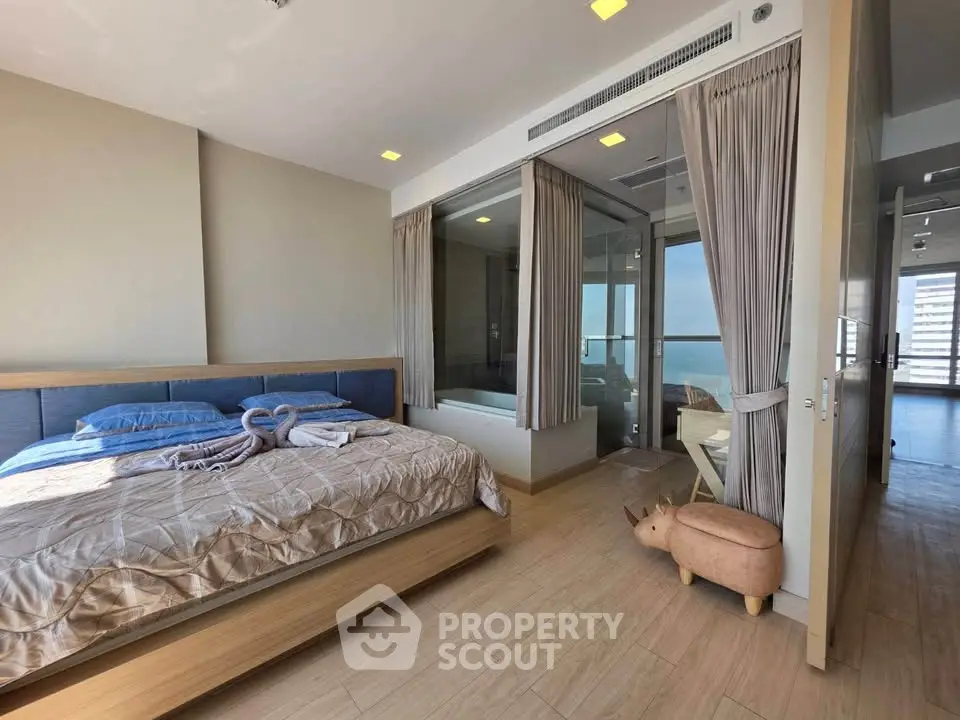 Spacious bedroom with modern decor and large windows offering stunning views, perfect for relaxation and comfort.