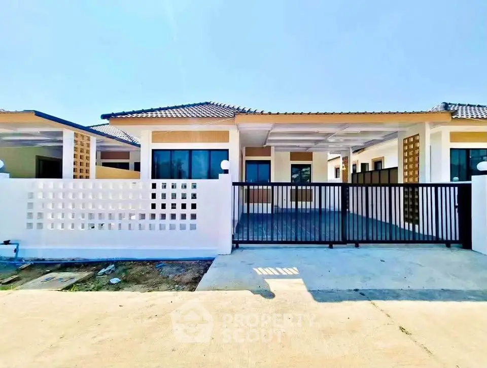 Modern single-story house with gated driveway and contemporary design.