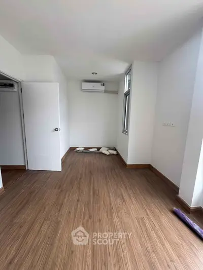 Spacious empty room with wooden flooring and air conditioning, perfect for customization.