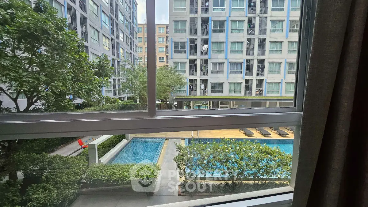 Modern apartment view with pool and lush greenery from window, perfect for urban living.