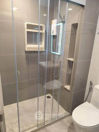 Modern bathroom with glass shower enclosure and sleek gray tiles