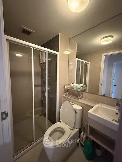 Modern bathroom with shower enclosure and sleek fixtures in contemporary apartment.