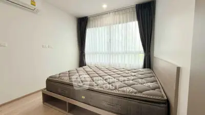 Cozy bedroom with large window and modern furnishings in a stylish apartment.