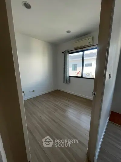 Cozy empty room with wooden flooring and air conditioning, perfect for customization.