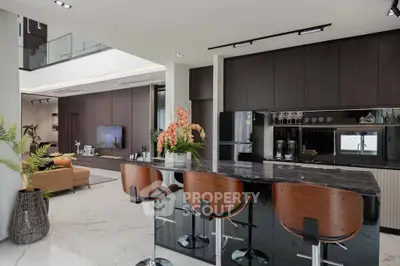 Luxurious modern kitchen with sleek design and stylish bar seating in open-concept living space.