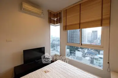 Cozy bedroom with city view, featuring large windows and modern air conditioning unit.