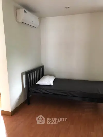 Minimalist bedroom with single bed and air conditioning, perfect for a cozy living space.