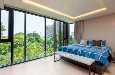 Luxurious bedroom with floor-to-ceiling windows offering stunning green views.