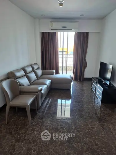 Spacious living room with modern sofa and TV, featuring elegant marble flooring and natural light.