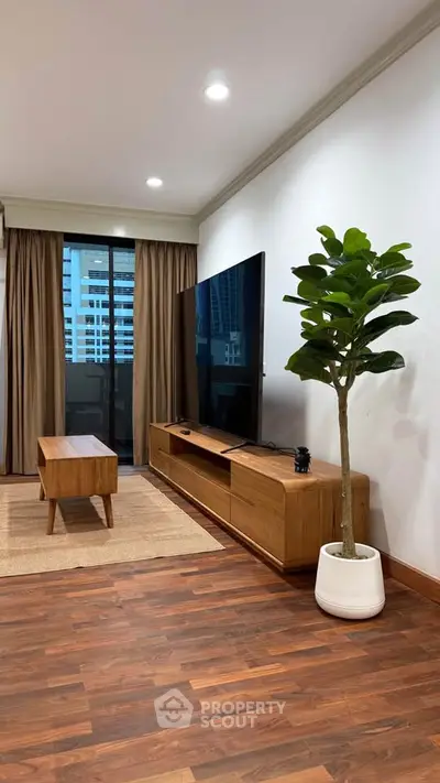 Modern living room with large TV, wooden furniture, and city view through window.