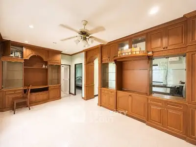 Spacious living room with elegant wooden cabinetry and ceiling fan