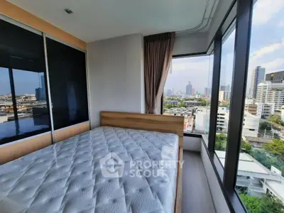 Modern bedroom with panoramic city view and large windows in a high-rise apartment.