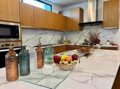 Luxurious modern kitchen with marble countertops and wooden cabinetry, featuring stylish decor and built-in appliances.