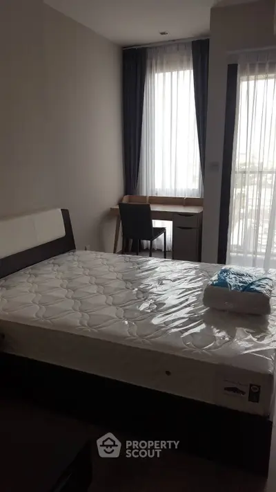 Cozy bedroom with natural light, featuring a comfortable bed and a study desk by the window.