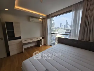 Modern bedroom with city view, featuring large window and sleek furnishings.
