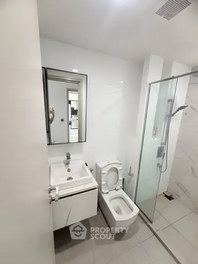 Modern bathroom with sleek fixtures and glass shower enclosure in a contemporary home.