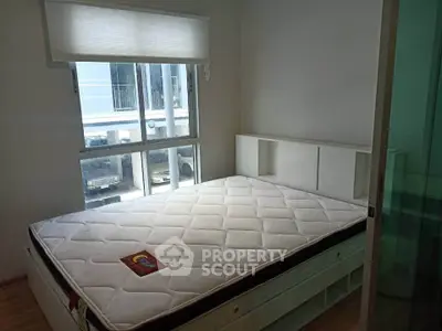 Cozy bedroom with large window and modern bed frame in a bright apartment.