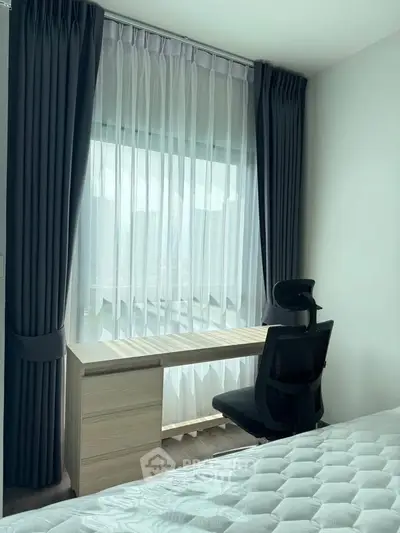 Cozy bedroom with study desk by a large window, perfect for work and relaxation.