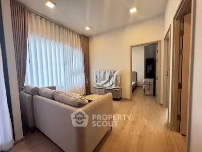 Modern living room with cozy beige sofa and wooden flooring, featuring elegant curtains and warm lighting.