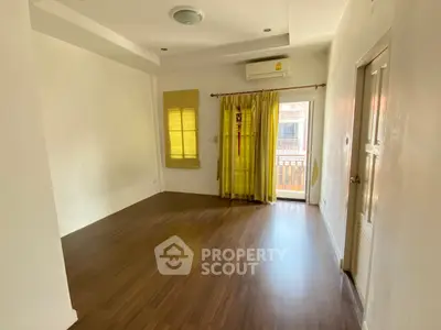 Spacious empty room with wooden flooring and balcony access, ideal for customization.