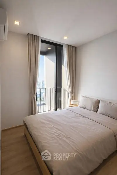 Modern bedroom with large window and city view, featuring minimalist decor and neutral tones.