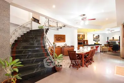 Luxurious open-plan living room with elegant staircase and dining area, perfect for entertaining.