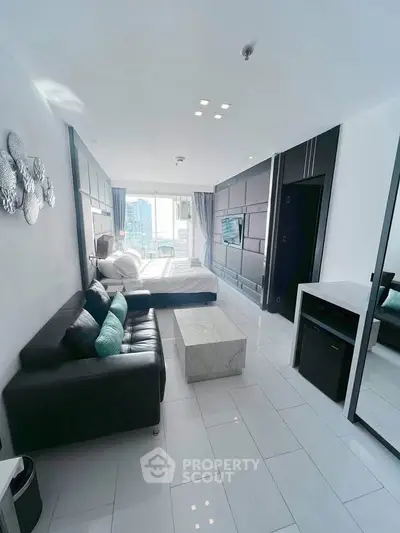 Modern studio apartment with sleek black and white decor, featuring a cozy bed and stylish sofa.