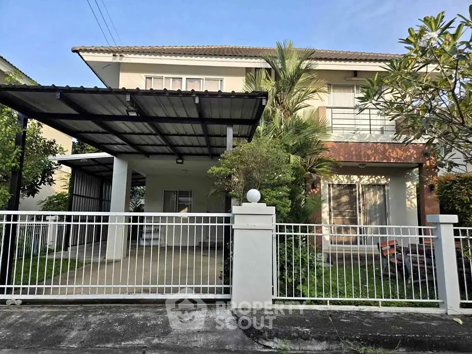 Charming two-story house with spacious carport and lush garden in a serene neighborhood.