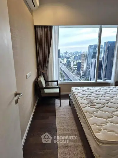 Modern bedroom with city view, featuring large window and elegant decor.
