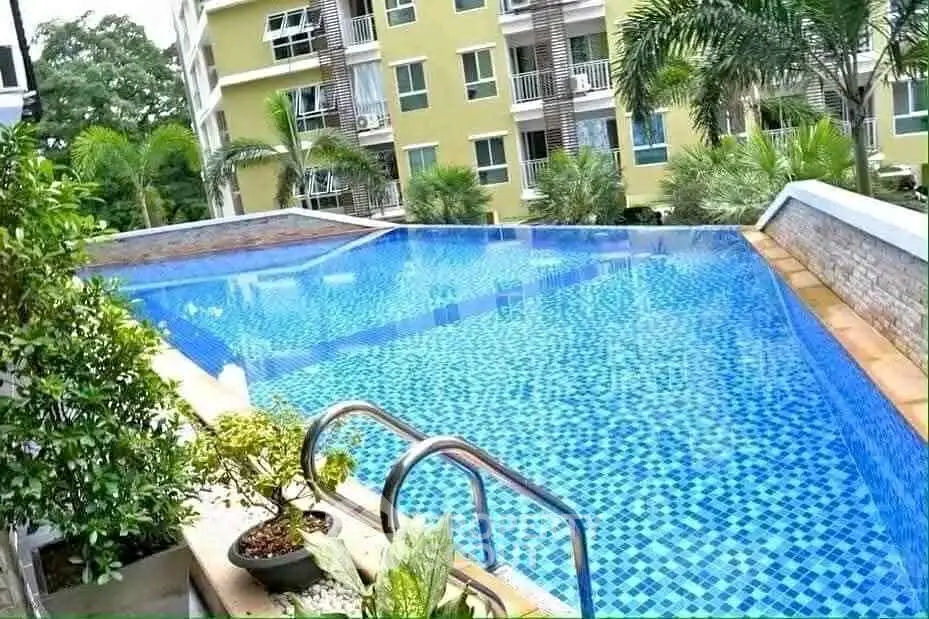 Luxurious apartment complex with stunning infinity pool and lush greenery.