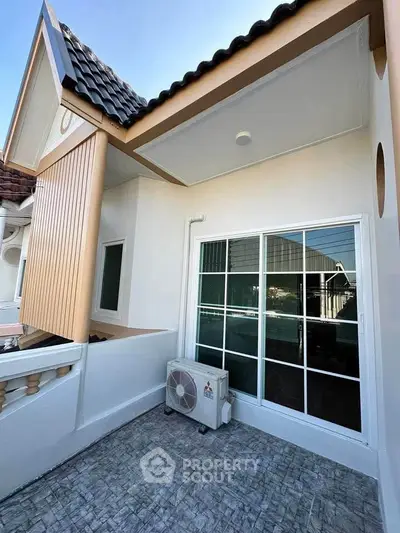 Charming balcony with sliding glass doors and air conditioning unit in modern residential building.